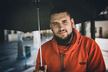 Man Wearing Orange Pullover Holding Black Umbrella