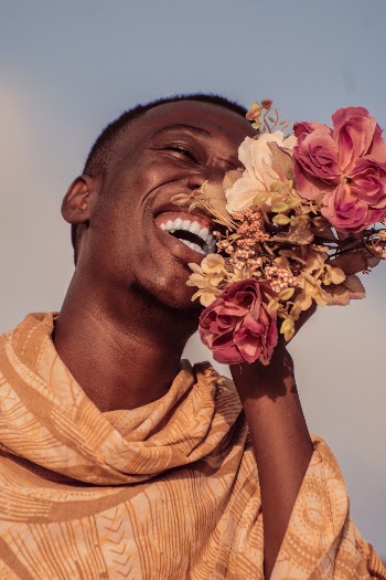 Man Wearing Orange Top Holding Flowers While Laughing