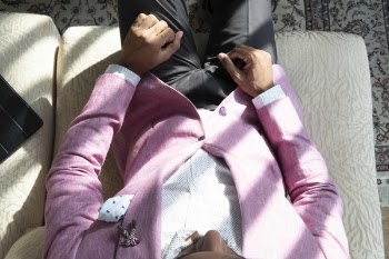 Man Wearing Pink Suit Jacket And Black Pants Sitting On Sofa