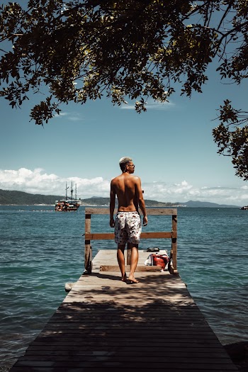 Man Wearing Printed Cargo Short Standing on Brown Wooden Boardwalk