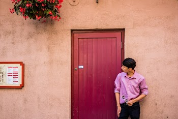 Man Wearing Purple  Shirt and Black Pants Standing Beside of Purple Wooden Door