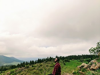 Man Wearing Red and Black Plaid Shirt Standing on Green Grass Hill