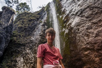 Man Wearing Red Crew-neck Shirt Standing Near Waterfalls