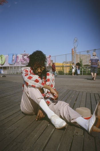 Man Wearing Red Plaid Shirt and Beige Trousers Sitting on Wooden Floor