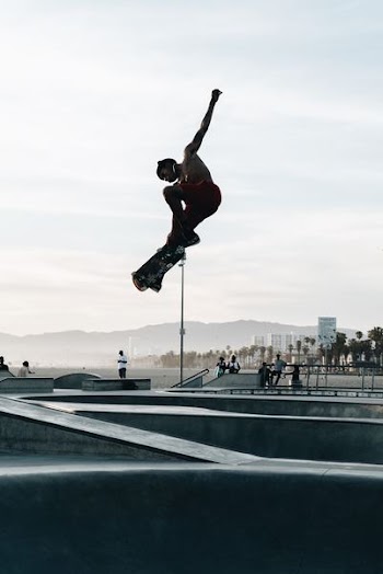 man wearing red shorts doing tricks on skateboard in skate park during daytime