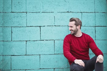 Man Wearing Red Sweatshirt and Black Pants Leaning on the Wall