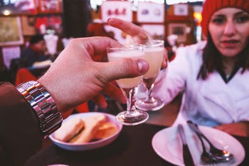 Man Wearing Silver Link Watch Holding a Glass Containing White Liquid in Front of a Woman