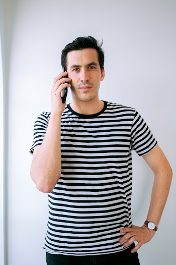 Man Wearing Stripped T-shirt Holding Phone on His Ear