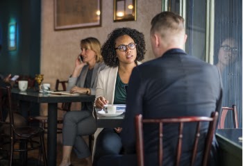 Man Wearing Suit Jacket Sitting on Chair in Front of Woman Wearing Eyeglasses