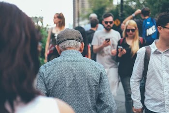 man wearing teal collard shirt walking through couple of people