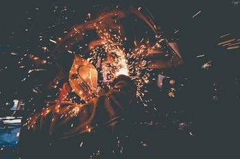 man wearing welding mask grinding metal