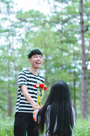 Man Wearing White and Black Striped Crew-neck Shirt Holding Red and Yellow Flowers