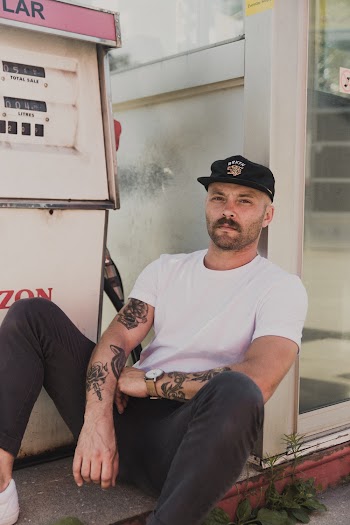 Man Wearing White Crew-neck Shirt Sitting Besides White Wall
