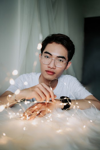 Man Wearing White Crew-neck T-shirt Sitting Near String Lights