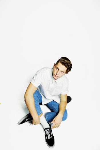 man wearing white dress shirt and blue denim jeans sitting on floor