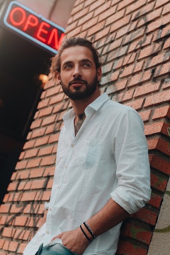 Man Wearing White Dress Shirt Leaning On Wall