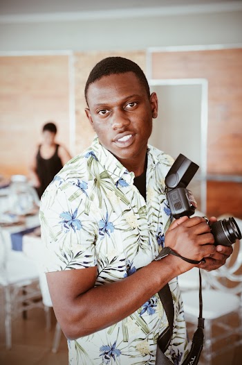 Man Wearing White Floral Shirt Holding a DSLR Camera