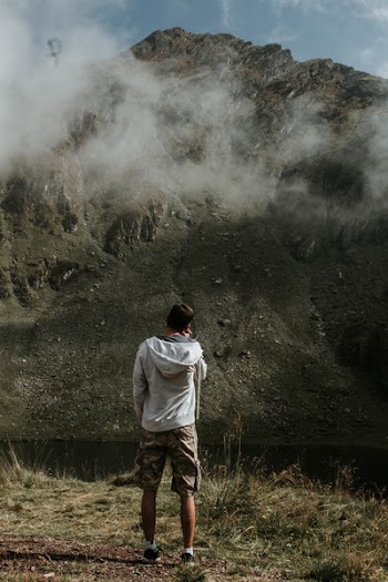 Man Wearing White Hoodie Standing Near Body of Water