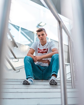 Man Wearing White Levi's Crew-neck Shirt Sitting on White Stair