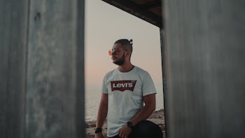 Man Wearing White Levi's Shirt Standing Outside Building Near Seashore