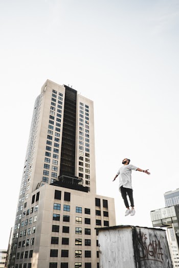 Man Wearing White Long Sleeve Shirt Beside White and Black High Rise Building