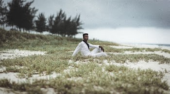 Man Wearing White Long-sleeved Shirt Sitting on Green Field