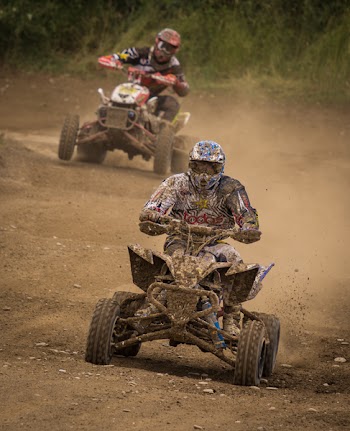 Man Wearing White Racing Outfit Stained With Mud Riding on Stained Mud Atv