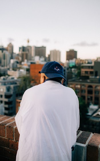 Man Wearing White Shirt and Blue Cap Looking at Buildings