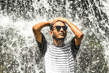 Man Wearing White Shirt and Sunglasses Standing on Waterfalls