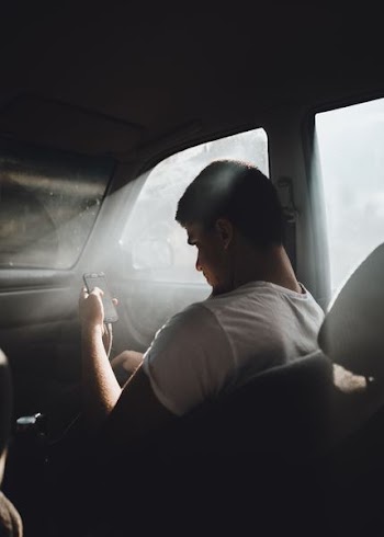 man wearing white shirt and using phone inside car