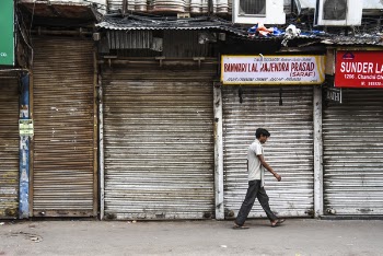 Man Wearing White Shirt Walking Beside Gray Building