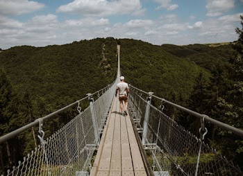Man Wearing White Shirt Walking On Bridge