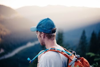 man wearing white shirt with orange hydro backpack