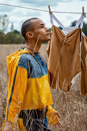 Man Wearing Yellow and Blue Jacket Standing on Brown Field