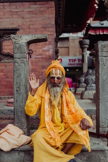 man wearing yellow long-sleeved coat sitting near pillar