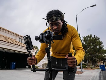 Man Wearing Yellow Long-sleeved Shirt Holding Camera Stand