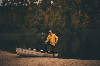 man wearing yellow pullover hoodie standing near white boat during daytime