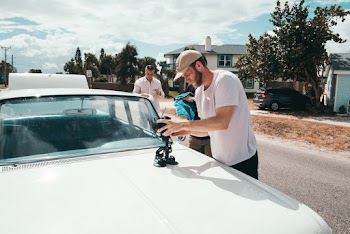 Man Wears White Crew-neck T-shirt Holding Camera on White Vehicle