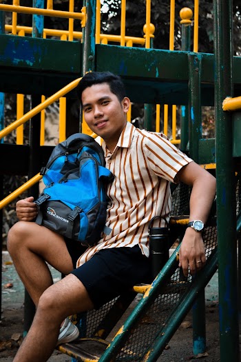 Man With Blue Backpack on Lap Sitting on Green Park Stairs