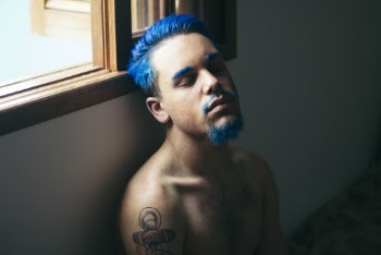 Man With Blue Hair Sitting In Front Of Brown Wood Frame Window Panel
