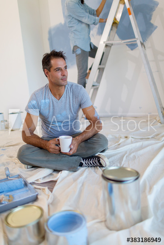 Man with coffee taking a break from painting room blue