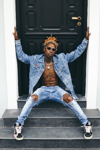 Man With Denim Jacket And Pants Sitting Next To Door