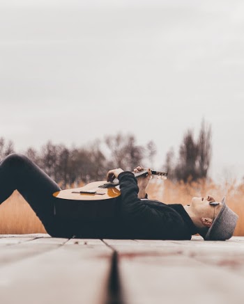 Man With Guitar Lying on Dock