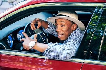 Man With Hat Driving A Red Car
