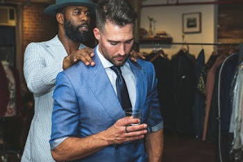 Man With Hat Massage the Man Wearing Blue Suit and Holding Glass
