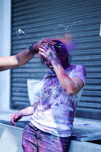 Man With Party Powders on His Shirt Standing in Front of Black Roller Shutter
