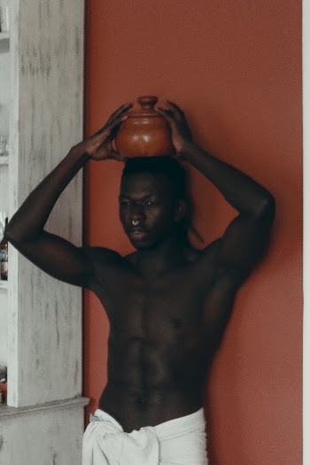 Man With Pot On Head While Leaning On Orange Wall