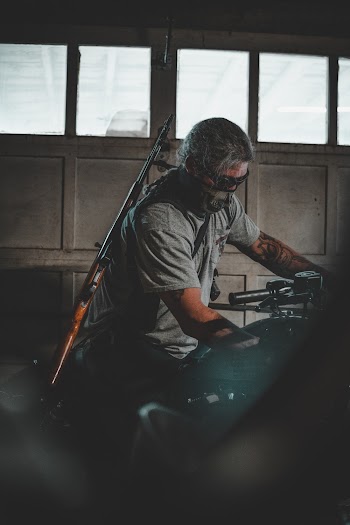 Man With Rifle Standing Near Motorcycle