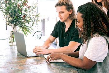 Man Working on a Laptop while Woman Takes Notes