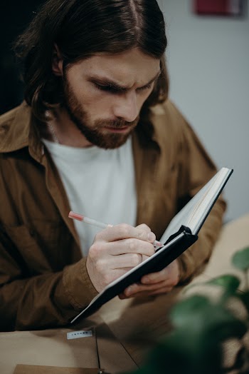 Man Writing on Notebook